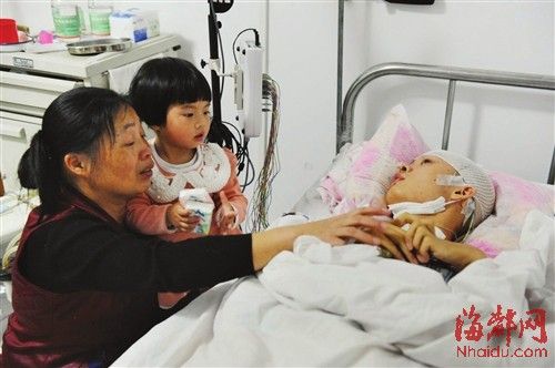 俞先生的母亲抚摩着他的手，其女儿在床边不时地说“爸爸买糖”